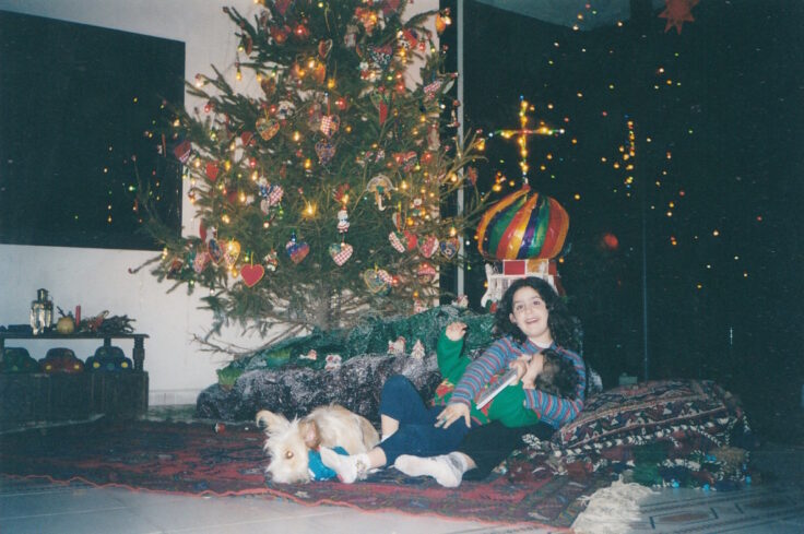 two siblings playing by the Christmas tree with a dog