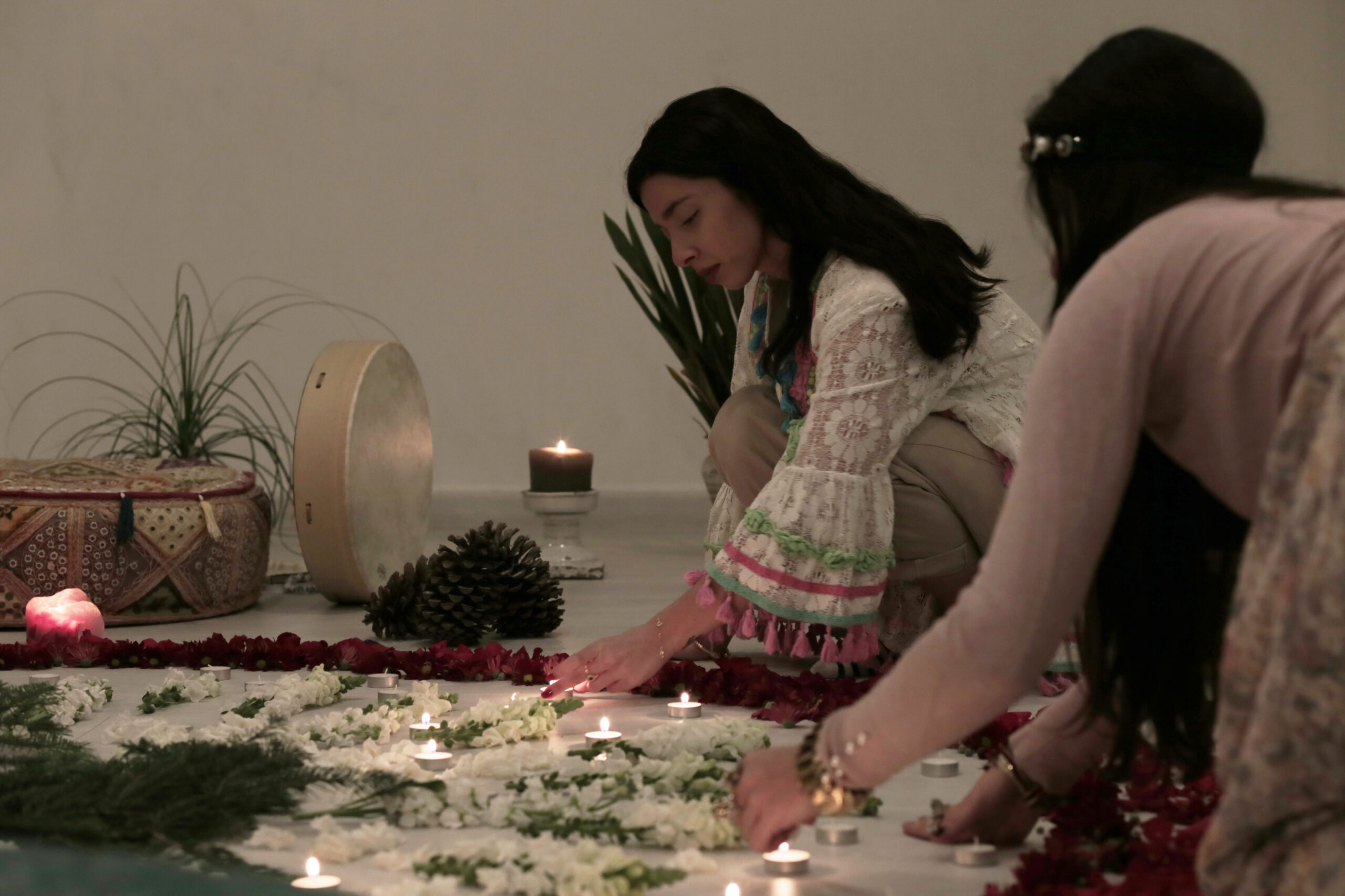 Two women lighting up candles for a meditation gathering