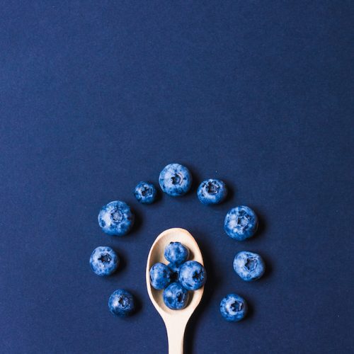 Fresh sweet blueberry fruit in the wooden spoon. Dessert healthy food. Group of ripe blue juicy organic berries. Raw summer diet. Delicious nature vegetarian ingredient. Black background.