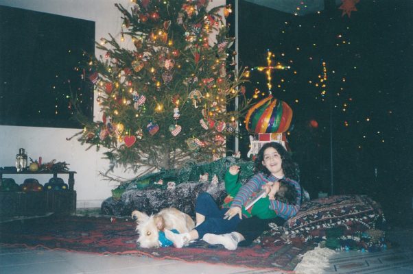 two siblings playing by the Christmas tree with a dog