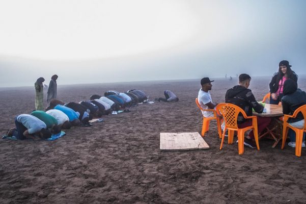 A group of men praying on a beach