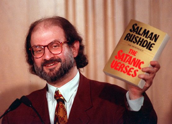 Novelist Salman Rushdie holds paperback copy of his controversial novel."The Satanic Verses" March 4, 1992 during a speech in Arlington, Va.. He spoke at an international conference on free expression sponsored by the Freedom Forum and American University. (AP Photo/Ron Edmonds)