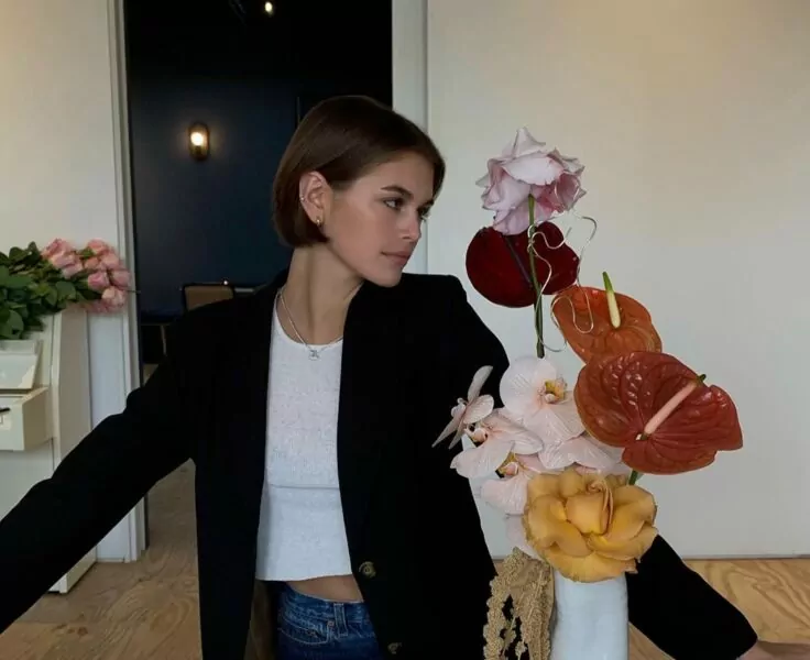 Kaia Gerber posing next to a vase of flowers