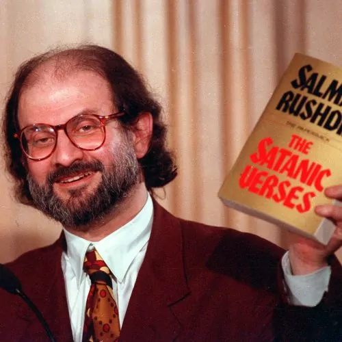 Novelist Salman Rushdie holds paperback copy of his controversial novel."The Satanic Verses" March 4, 1992 during a speech in Arlington, Va.. He spoke at an international conference on free expression sponsored by the Freedom Forum and American University. (AP Photo/Ron Edmonds)